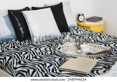 Decorative tray with book,tea set and gloves on the bed