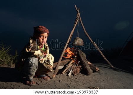 Bromo, JAVA, INDONESIA - May 11, 2013. : Unidentified kid near the fire, Indonesia has a tropical climate, with variations compared to the coastline and lowlands cool weather from June to September.
