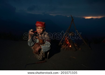Bromo, JAVA, INDONESIA - May 11, 2013. : Unidentified woman near the fire, Indonesia has a tropical climate,with variations compared to the coastline and lowlands cool weather from June to September.