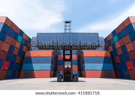 Forklift truck lifting cargo container in shipping yard for import,export, logistic industrial with container stack background