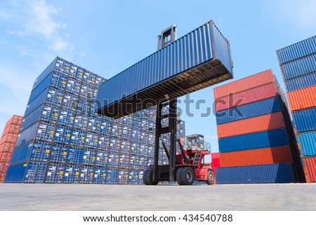 Forklift truck lifting cargo container in shipping yard or dock yard with cargo container stack in background for transportation import,export and logistic industrial concept