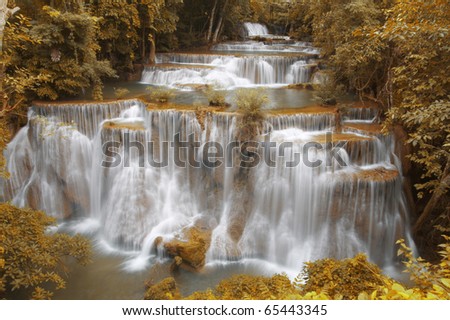 big waterfall with brown leaves in autumn