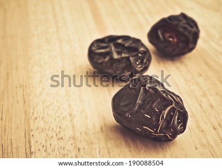 Ajwa Dates fruit on wooden table in retro style (Ajwa is a soft dry variety of date fruit from Saudi Arabia. It is cultivated at the city of Madinah)