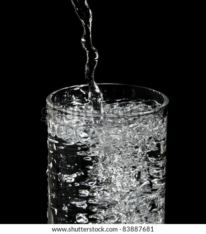 filling water into glass and black background