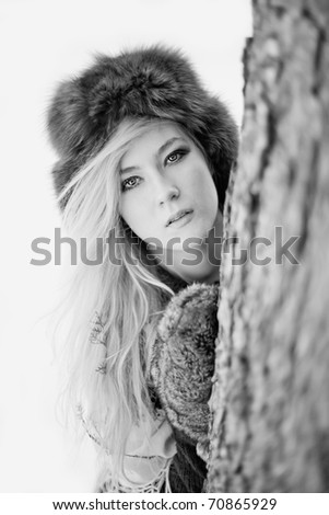 Young caucasian blonde wearing blue sweater, furry hat with gloves and traditional shawl in winter scenery.