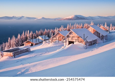 abandoned snow-covered hut (cabins) in the mountains at sunrise