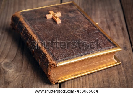 old closed holly Bible with wooden christian cross