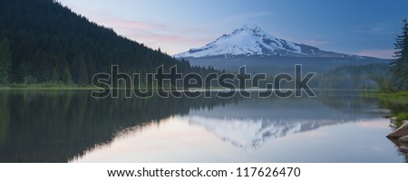 Panorama view of volcano mountain Mt. Hood, in Oregon, USA. At sunset with reflection on the water of the Trillium lake.