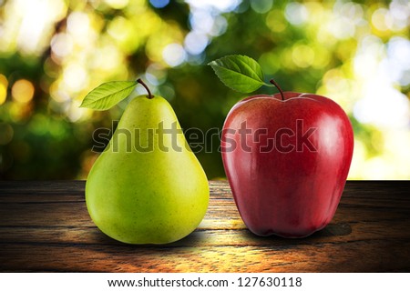 Apple and Pear on wood with summer scene background