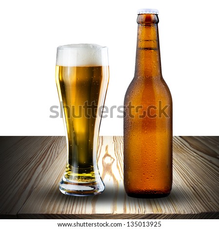 Bottle and glass of cold beer on wood with white background
