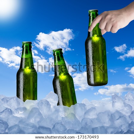Hand Holding Cold Beer Bottle from Ice Cubes in Hot Summer Day