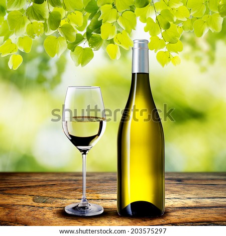 White Wine Bottle and Glass on wood table with summer scene background
