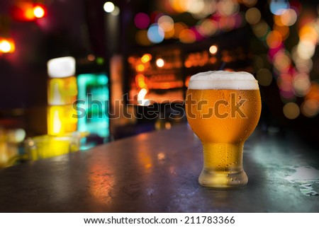 Beer on bar with night scene in background