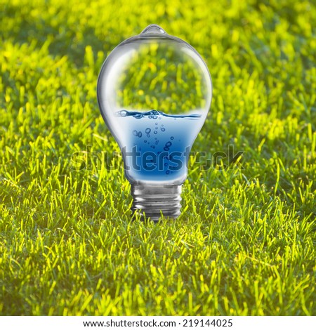 Light bulb with water inside on green grass. Concept of Eco technology