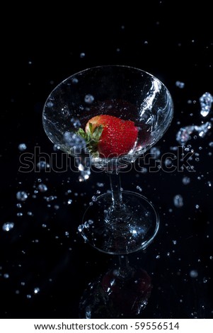 Strawberry splash in martini glass isolated on black background