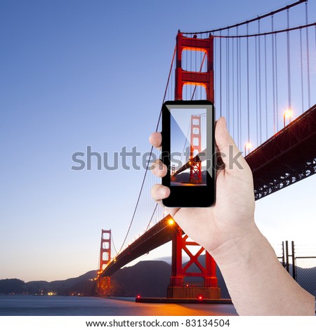 Cell phone in hand and golden gate view on sunny day