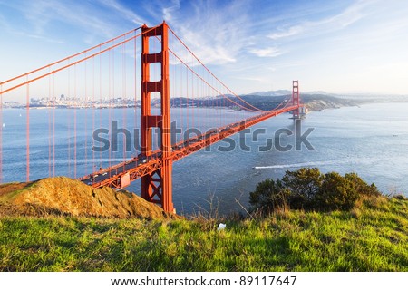 Golden Gate in clear blue sky with green grass as foreground. San Francisco, USA.