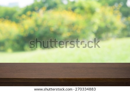 Empty wooden deck table with blured yellow plant background, for product display montage