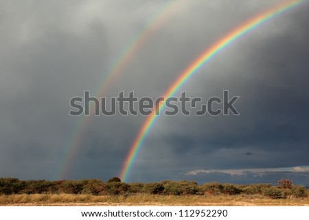 Rural landscape with a colorful rainbow and heavy rain clouds, southern Africa