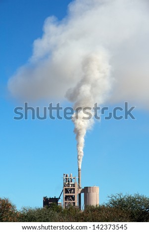 Smoke from an industrial plant drifting in the wind against a blue sky