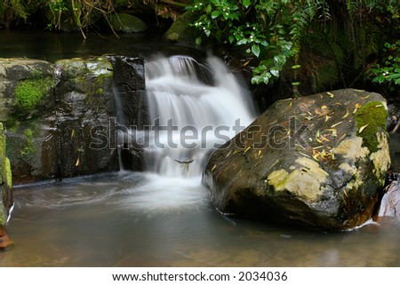 Small waterfall in a mountain stream with moss covered rocks
