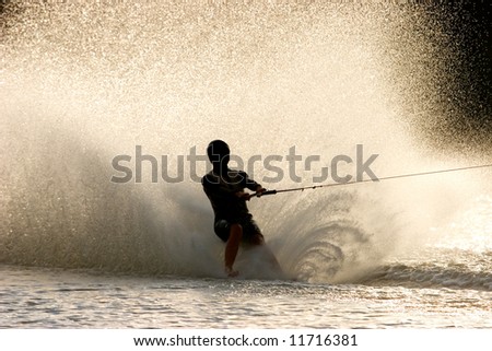 Silhouette of a barefoot water skier with backlit water spray