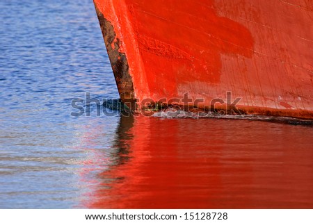 Red hull of a boat with reflection in the water