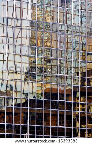 Abstract, distorted image of a building reflected in the windows of a tall city building