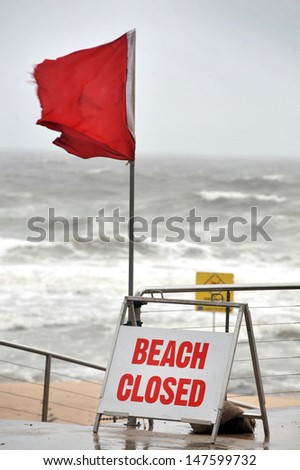 beach closed sign and red flag