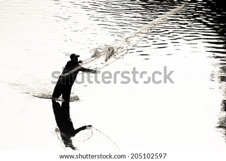 Silhouette of a male throwing a cast net to catch fish silhouette