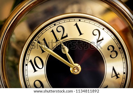 Golden clock face.  Hands showing five minutes to midnight.