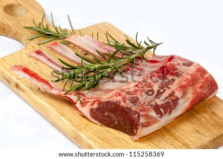 Rack of lamb with rosemary on a wooden board.