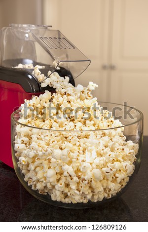 Bowl of popcorn with popcorn machine on a kitchen bench.  Healthy home-made snacking.