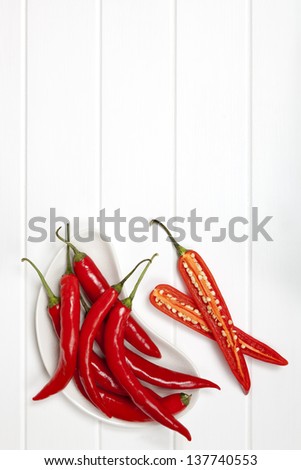 Red chili peppers over white painted timber paneling.  Food background with lots of copy-space.