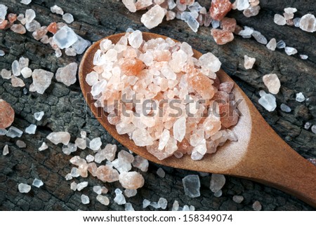 Spoonful of pink Himalayan rock salt, over weathered timber.