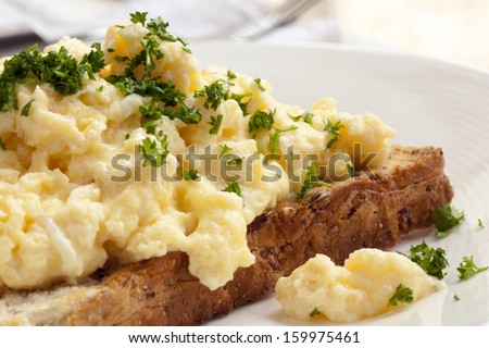 Scrambled Eggs On Toasted Wholegrain Bread. Garnished With Parsley.