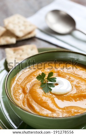 Pumpkin soup with crackers.  Served in green soup bowl.