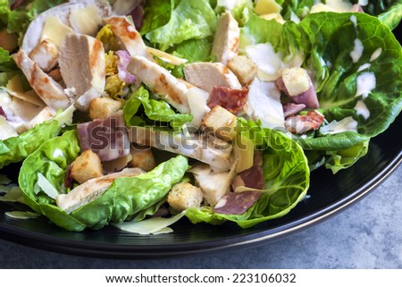 Chicken caesar salad on black plate.