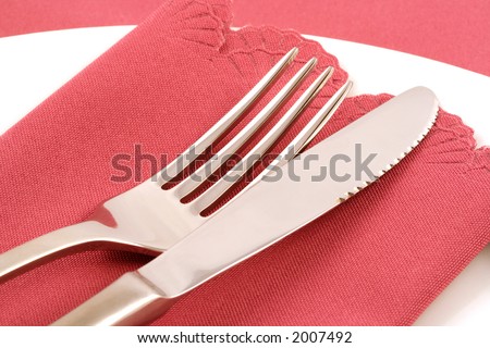 White plate, silver knife and fork, and dusky pink napkin and tablecloth