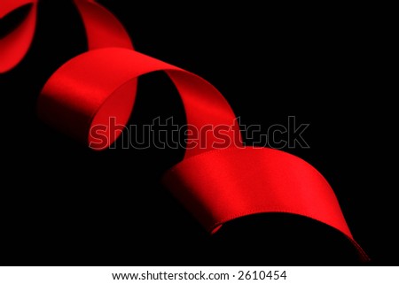 A spiral of red satin ribbon, on a black background.