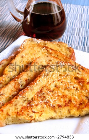 A plate of french toast, with a jug of maple syrup.  Vertical presentation