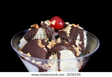 A chocolate sundae with chopped nuts and a cherry on top.
