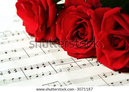 Three red roses resting on sheet music (\