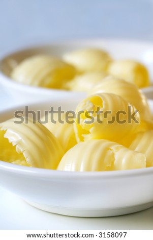 Butter curls in small white butter dishes.