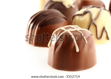 Fancy chocolates, with focus on front chocolate.  Includes milk chocolate, dark chocolate, white chocolate, truffles.