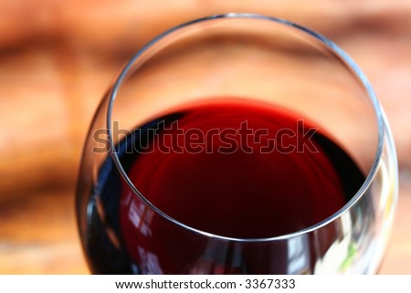 Closeup of a glass of red wine in natural light.  Focus on front lip of glass.