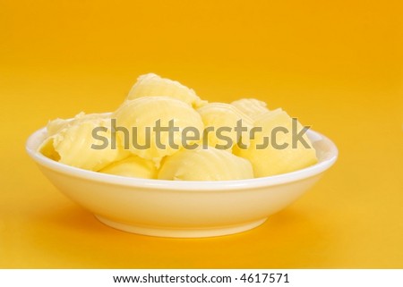 Butter curls in a butter dish, with golden yellow background.