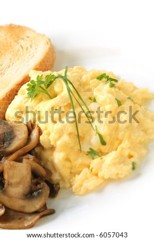 Scrambled eggs with mushrooms and toast, garnished with parsley and chives.