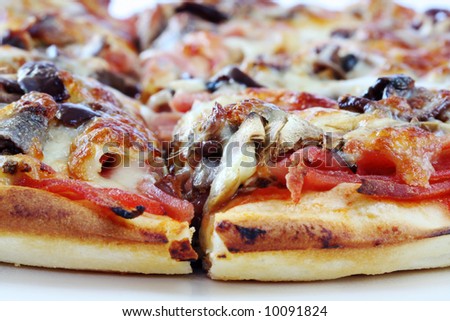 Pizza in close-up, straight from the oven.  Melting mozzarella cheese over tomato base with mushrooms, olives, mushrooms and anchovies.