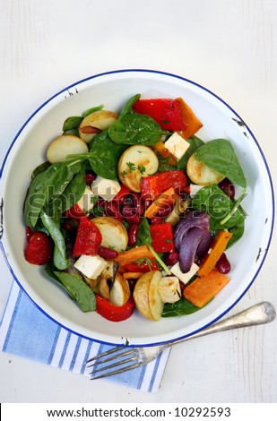 Salad of roasted vegetables, kidney beans, spinach, and goat\'s cheese.  In old enamel bowl.